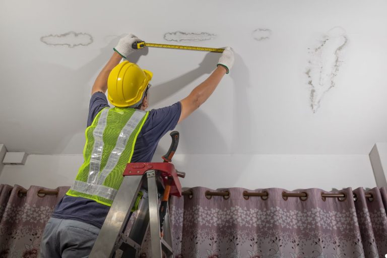 A man measuring the ceiling with a tape measure, focused on ensuring accurate dimensions for a project.